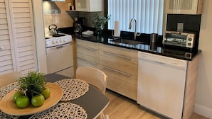 A compact kitchen with a stove, sink, and dishwasher. There is a dining table with a placemat and a potted plant. - LOCATION! LOCATION! LOCATION!  Best location in Orlando (Orlando)