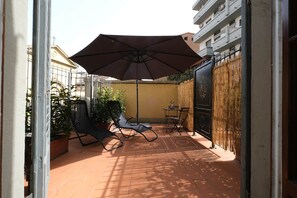 A patio with two lounge chairs, a table, and an umbrella. - Vin Novo Rooms & Apartments (Florence)