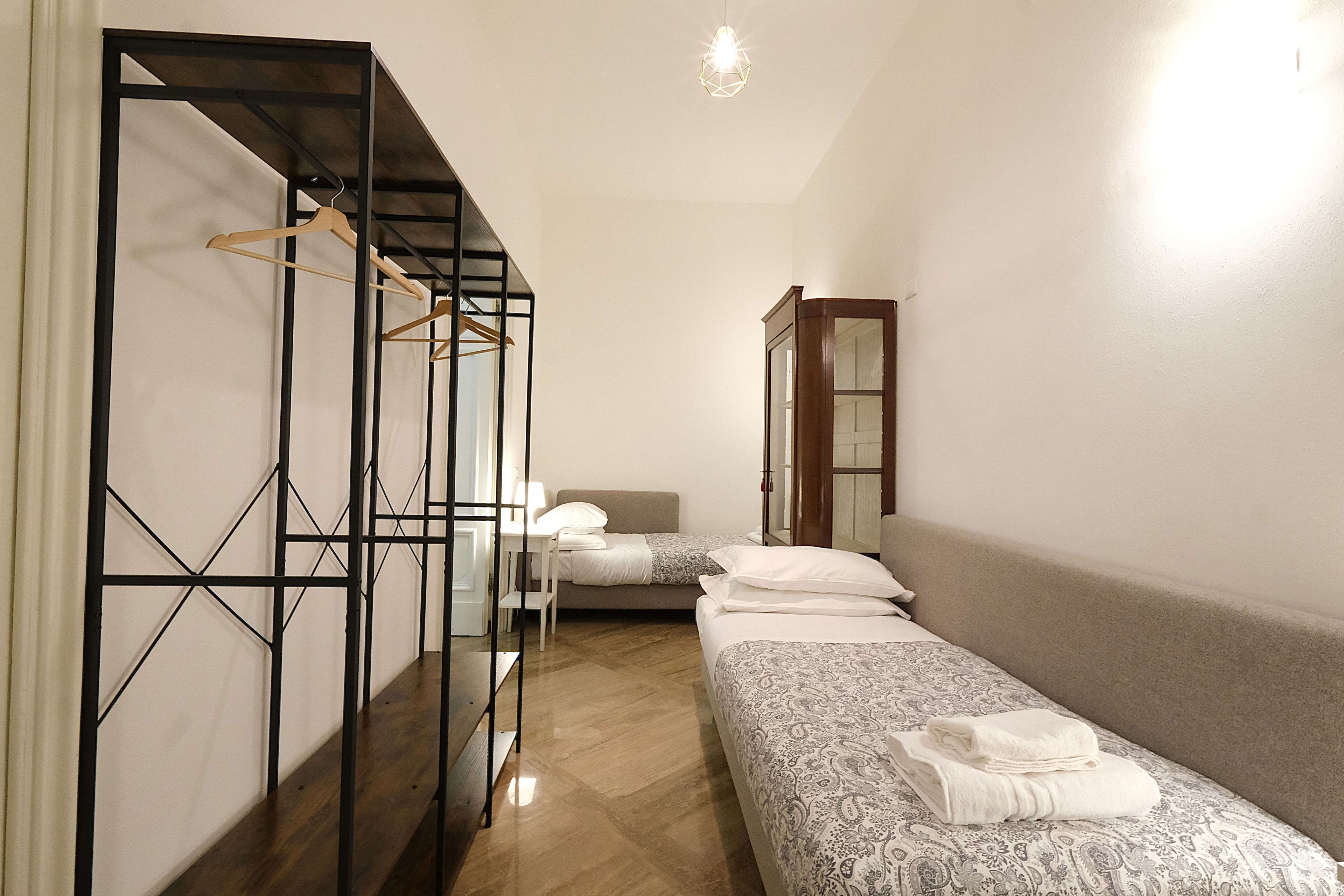 Quarto com cama, guarda-roupa, escrivaninha e luminária pendente.