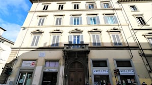 Un edificio con una entrada central amplia, múltiples ventanas con contraventanas, y letreros que indican los servicios 'L'Hotelline' y 'Wash & Dry'.
