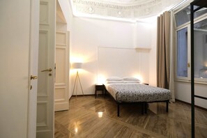 A bedroom with a bed, bedside table, lamp, and a window with curtains. - Vin Novo Rooms & Apartments (Florence)