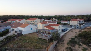 Un quartier résidentiel où les maisons se distinguent par leurs toits recouverts de tuiles rouges, une route asphaltée et un chemin de terre.