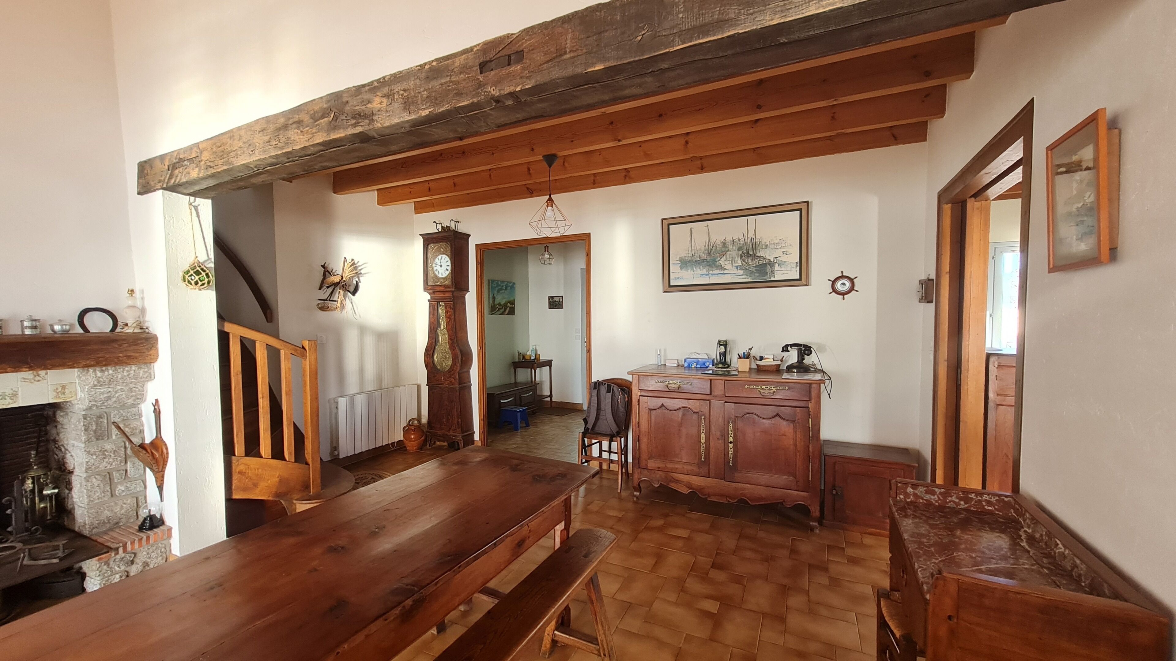Ein rustikaler Essbereich mit einem Holztisch, Bänken und einem Kamin aus Stein.
