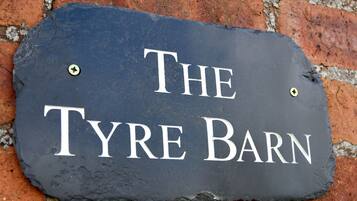 Un letrero de pizarra con el texto 'The Tyre Barn' colocado en una pared de ladrillo.