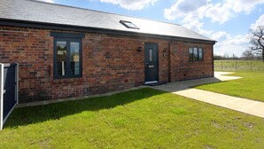 A brick building with a flat roof, a black door, and two windows. - The Tyre Barn (Whitchurch)
