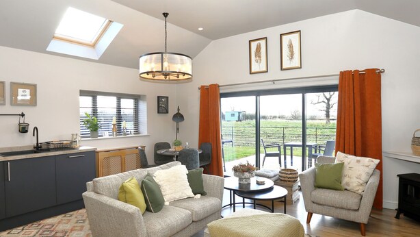 A modern kitchen with a skylight, a dining area with a round table, and a living room with two sofas and a coffee table. - The Tyre Barn (Whitchurch)