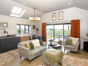A modern kitchen with a skylight, a dining area with a round table, and a living room with two sofas and a coffee table. - The Tyre Barn (Whitchurch)