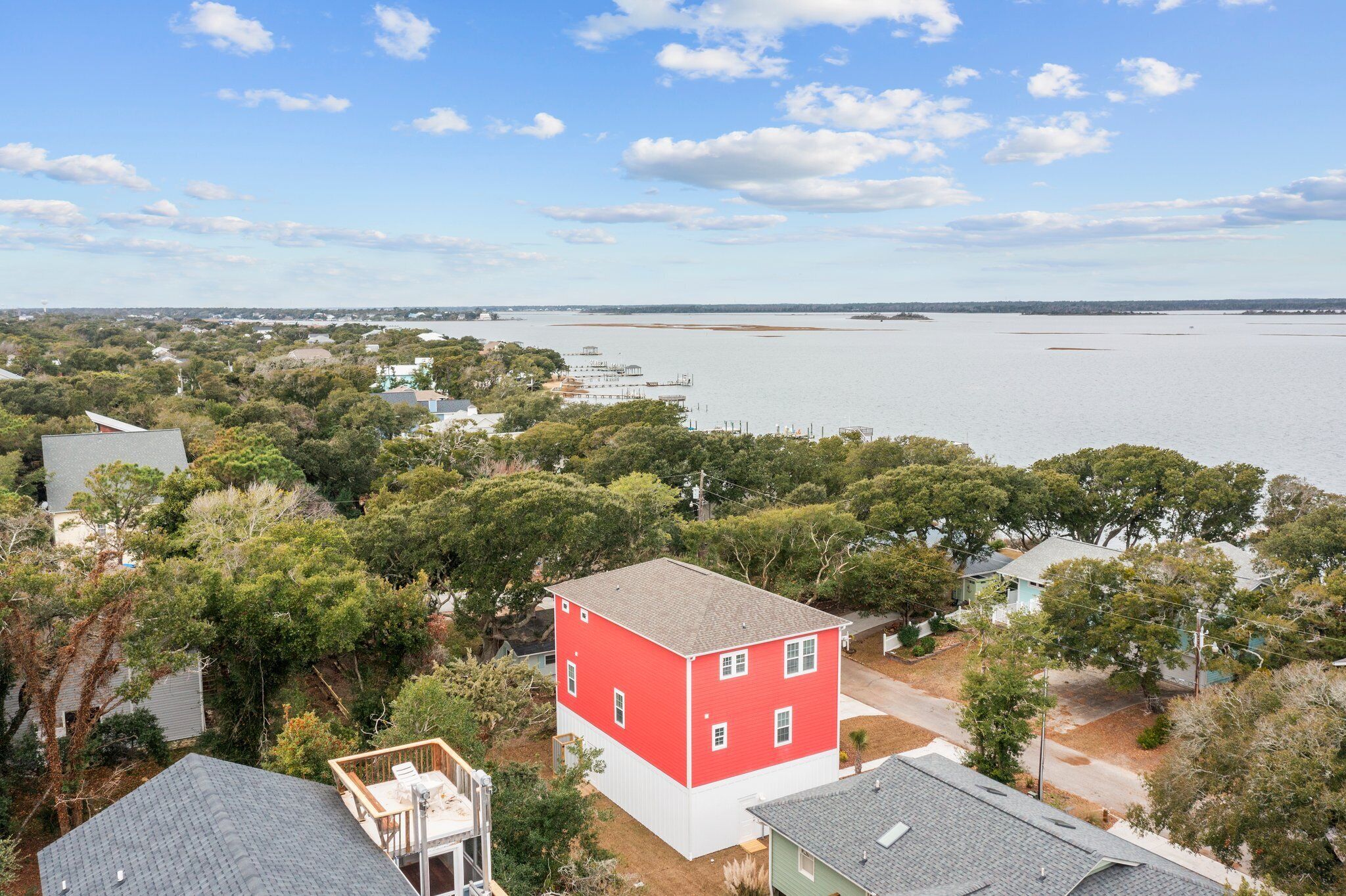 A red building surrounded by trees, with a view of a large body of water and distant shoreline.