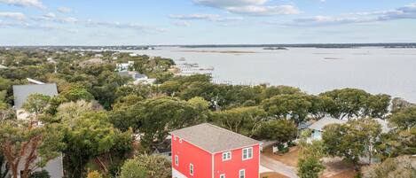 A red building surrounded by trees, with a view of a large body of water and distant shoreline.