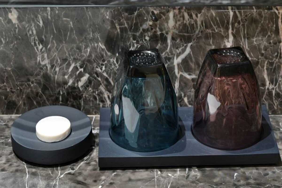 A marble countertop with two glass objects on a black base.