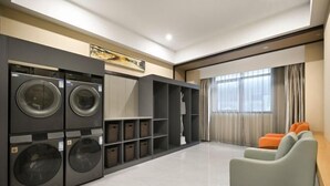 A modern apartment with a built-in washer and dryer, a sofa, and a large window. - Dongguan Xiegang FONTOO Hotel (Dongguan)