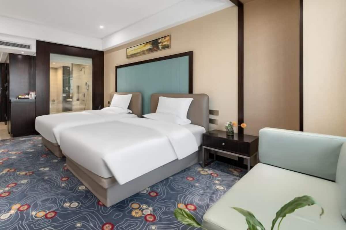 A hotel room with a large bed, a bedside table, a chair, and a view of the bathroom.