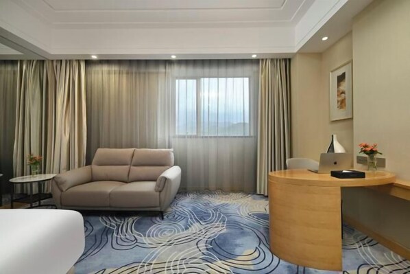 A hotel room with a sofa, a desk with a laptop, a small table with a vase, and a large window with curtains. - Dongguan Xiegang FONTOO Hotel (Dongguan)