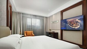 A hotel room with a large bed, a desk, a chair, and a television on the wall. - Dongguan Xiegang FONTOO Hotel (Dongguan)