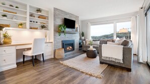 A modern living room with a fireplace, a sofa, a TV, and a bookshelf. - Serene & Modern~ Ocean Front View~ 2 Bd 2 Bth~1st Fully Remodeled (Watsonville)