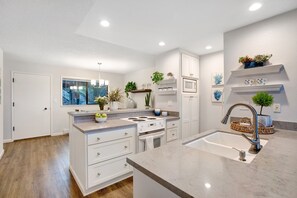 A modern kitchen with white cabinetry, a built-in stove, and a large island with a sink.
