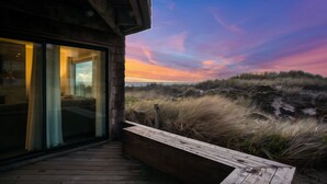 A wooden deck with a glass door leading to a room with a bed. - Serene & Modern~ Ocean Front View~ 2 Bd 2 Bth~1st Fully Remodeled (Watsonville)