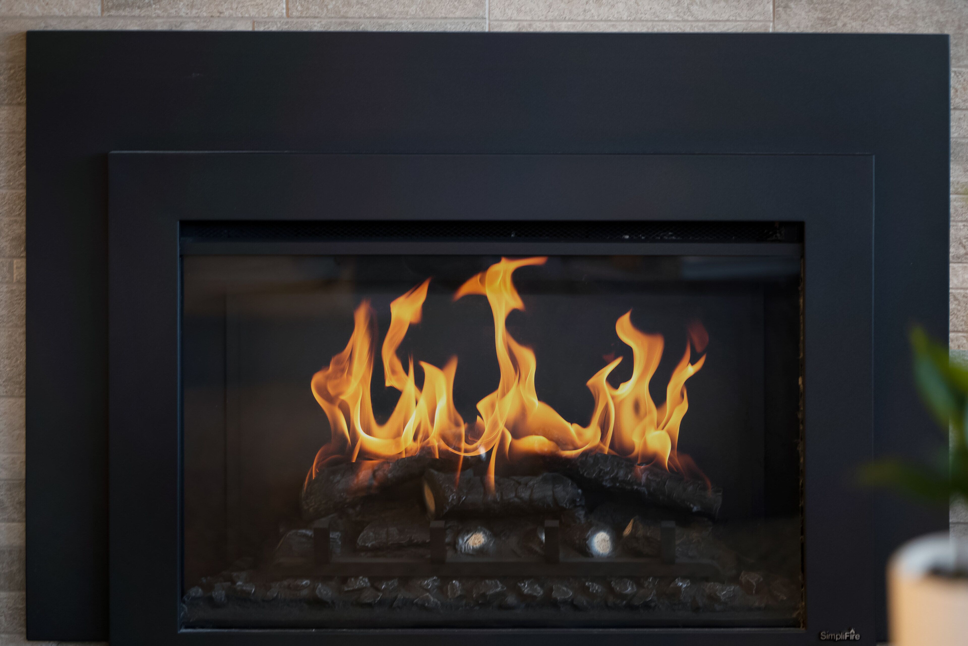 Ein Kamin mit Glasfront, in dem ein Feuer brennt.