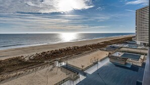 A beach view from a hotel balcony with a clear sky, a sandy beach, and a calm sea.
