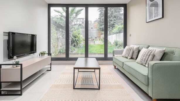 A modern living room with a flat-screen TV, a green sofa, and a coffee table.