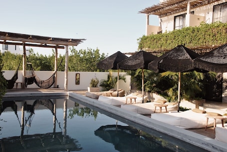 Una piscina al aire libre, sombrillas, sillones reclinables de piscina