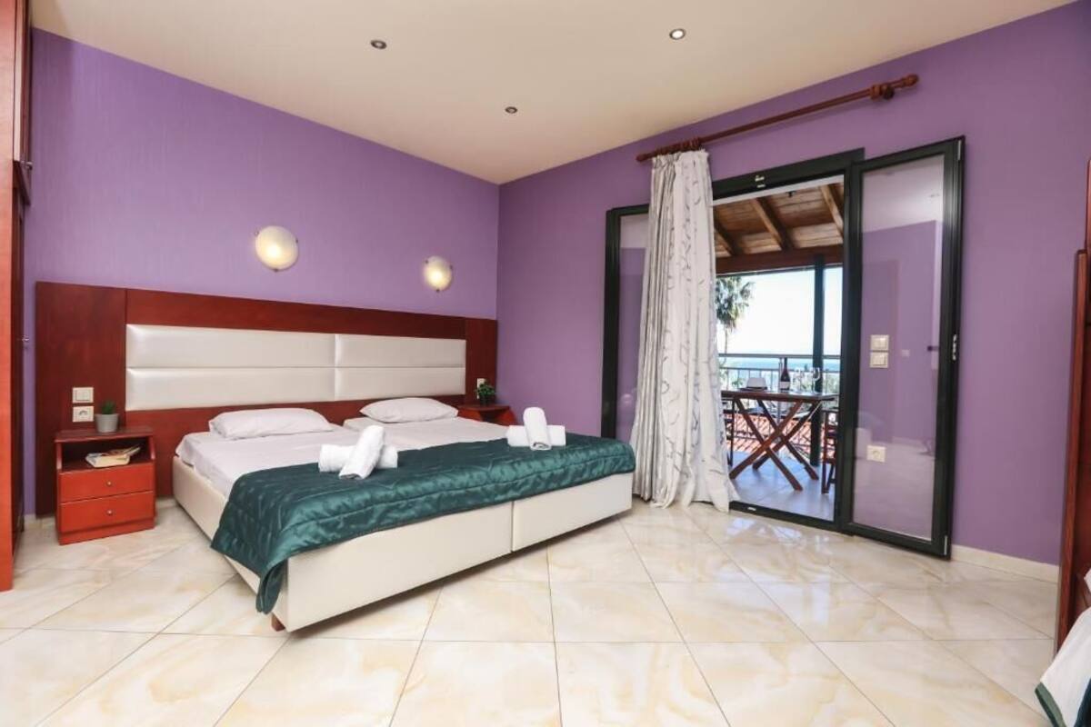 Ein Schlafzimmer mit Bett, Nachttisch, Fenster mit Vorhängen und Blick ins Freie.