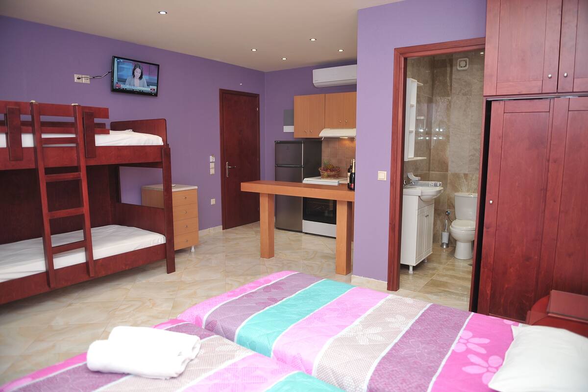 Ein Schlafzimmer mit Etagenbetten, einer kleinen Küchenzeile und einem Badezimmer.