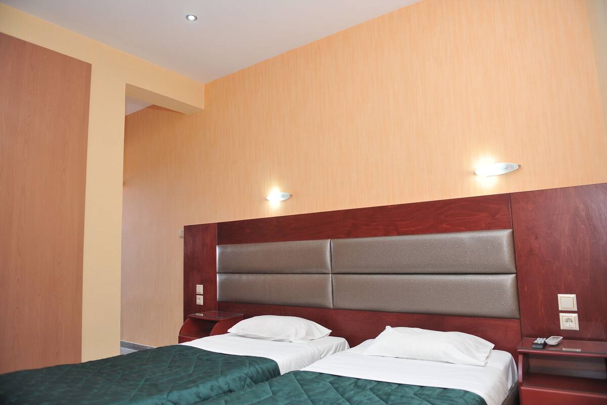 Ein Hotelzimmer mit zwei Betten, Holz-Kopfteilen und Nachttischen mit Lampen.