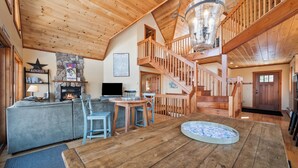 Amplia sala de estar con chimenea, una mesa de comedor y una escalera que sube a un nivel superior.
