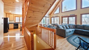 Amplia sala de estar con escalera de madera, un ventanal y vistas al exterior.