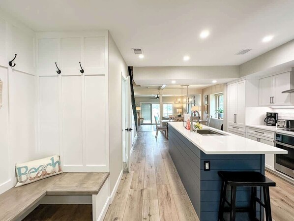 A modern kitchen with white cabinetry, a central island, and a dining area in the background.