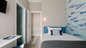 A hotel room with a bed, a desk, and a chair. - Anjoy & Bleev Rooms | SARDINA | Queen French bed room (Rho)