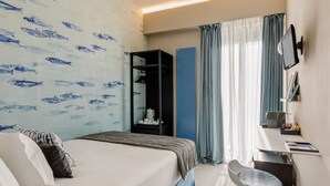 A hotel room with a bed, a desk, a chair, a wardrobe, and a TV. - Anjoy & Bleev Rooms | SARDINA | Queen French bed room (Rho)