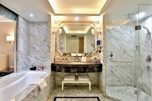 A modern bathroom with a marble vanity, a large mirror, a bathtub, and a glass-enclosed shower. - Jincheng International Hotel (Jinhua)