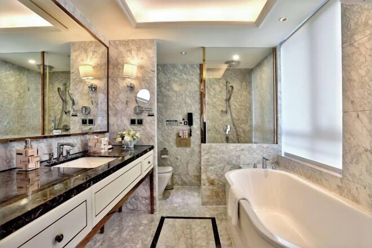 A modern bathroom with a large mirror, a bathtub, and a shower.