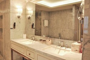A modern bathroom with two sinks, a large mirror, and marble walls.