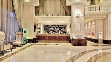 A lobby with a reception desk, a chandelier, and a marble floor.