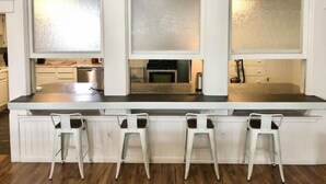 A kitchen with a central island, three bar stools, and frosted glass windows. - 4Bd 2Ba Converted Historic Church in Uptown Butte! (Butte)