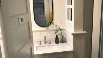 A bathroom with a white vanity, a large mirror, and a sink.