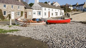 A coastal building with a stone facade and a white upper section. - 14 Parc Delfryn (Brynteg)