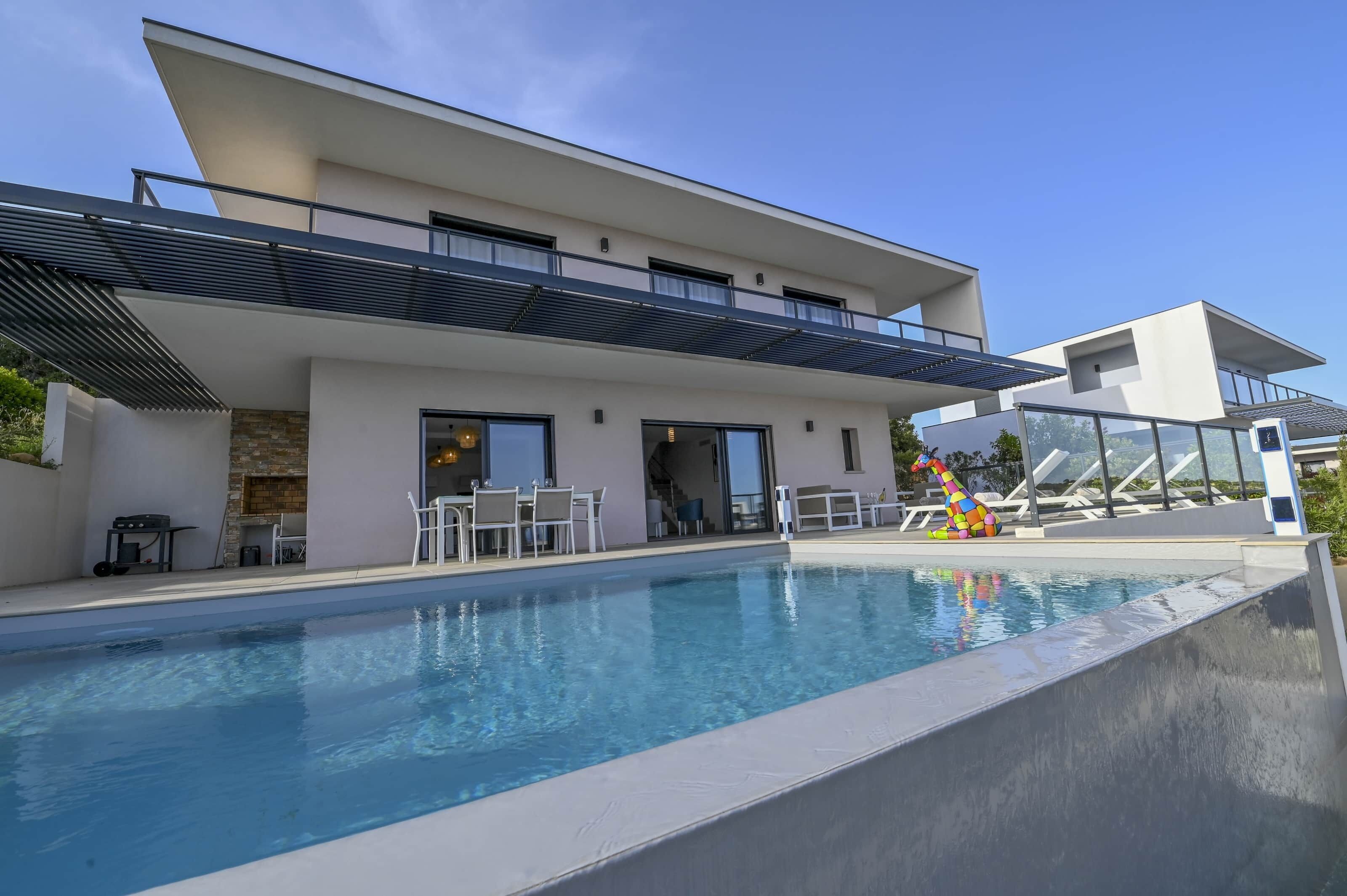 A modern house with a swimming pool, outdoor seating, and a slide.