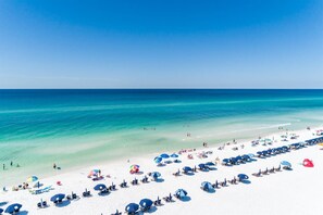 Una spiaggia con sabbia bianca, acqua cristallina turchese e numerosi ombrelloni.
