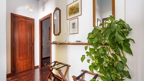 A hallway with wooden flooring, a wooden door, a mirror, a shelf with a plant, and a hanging light fixture. - LA VITA E' BELLA (Sorrento)