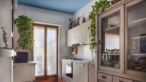 A kitchen with wooden cabinets, a stove, and a large window. - LA VITA E' BELLA (Sorrento)