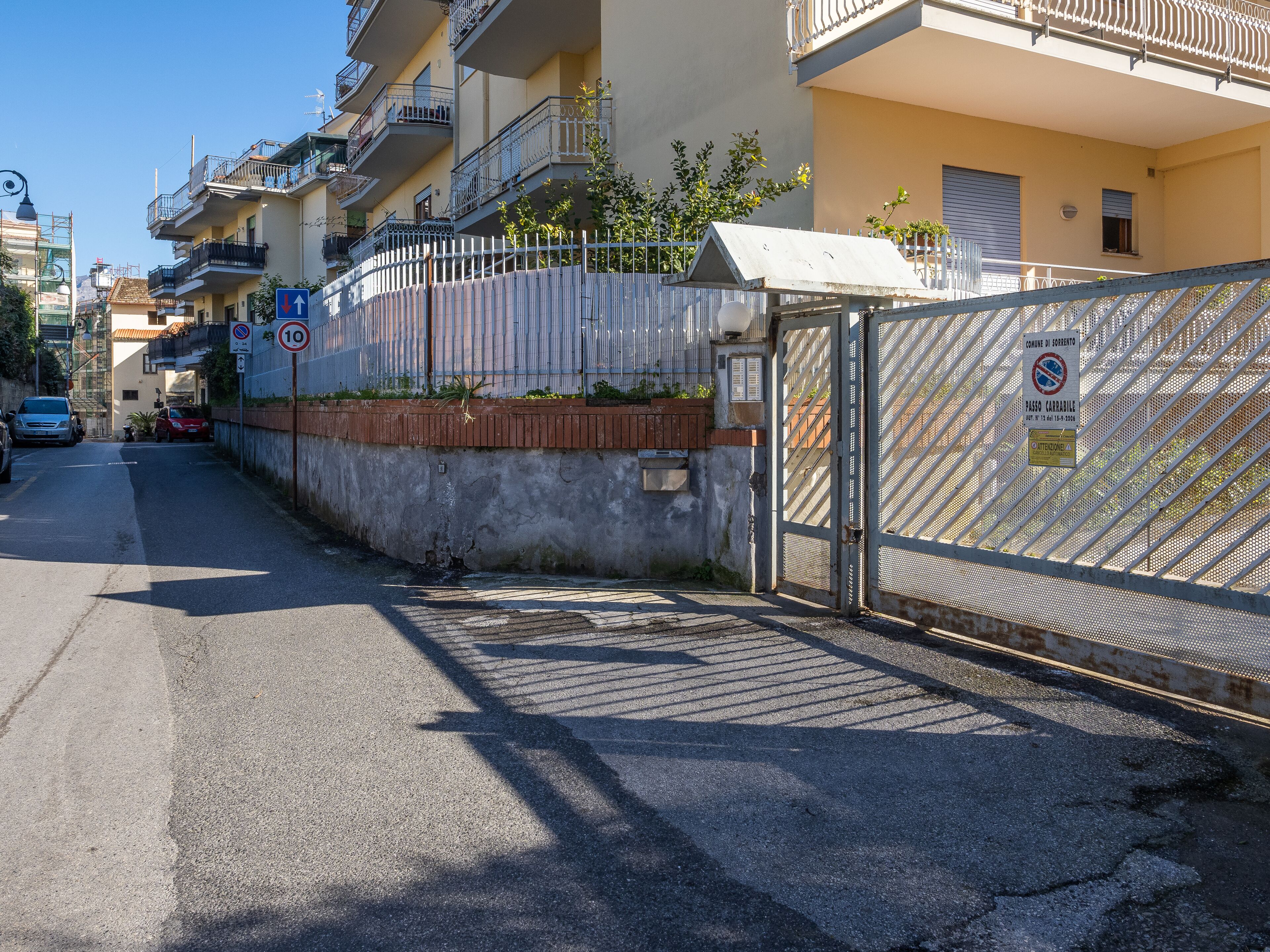 A gated residential area with a metal fence, a brick wall, and a clear sky.