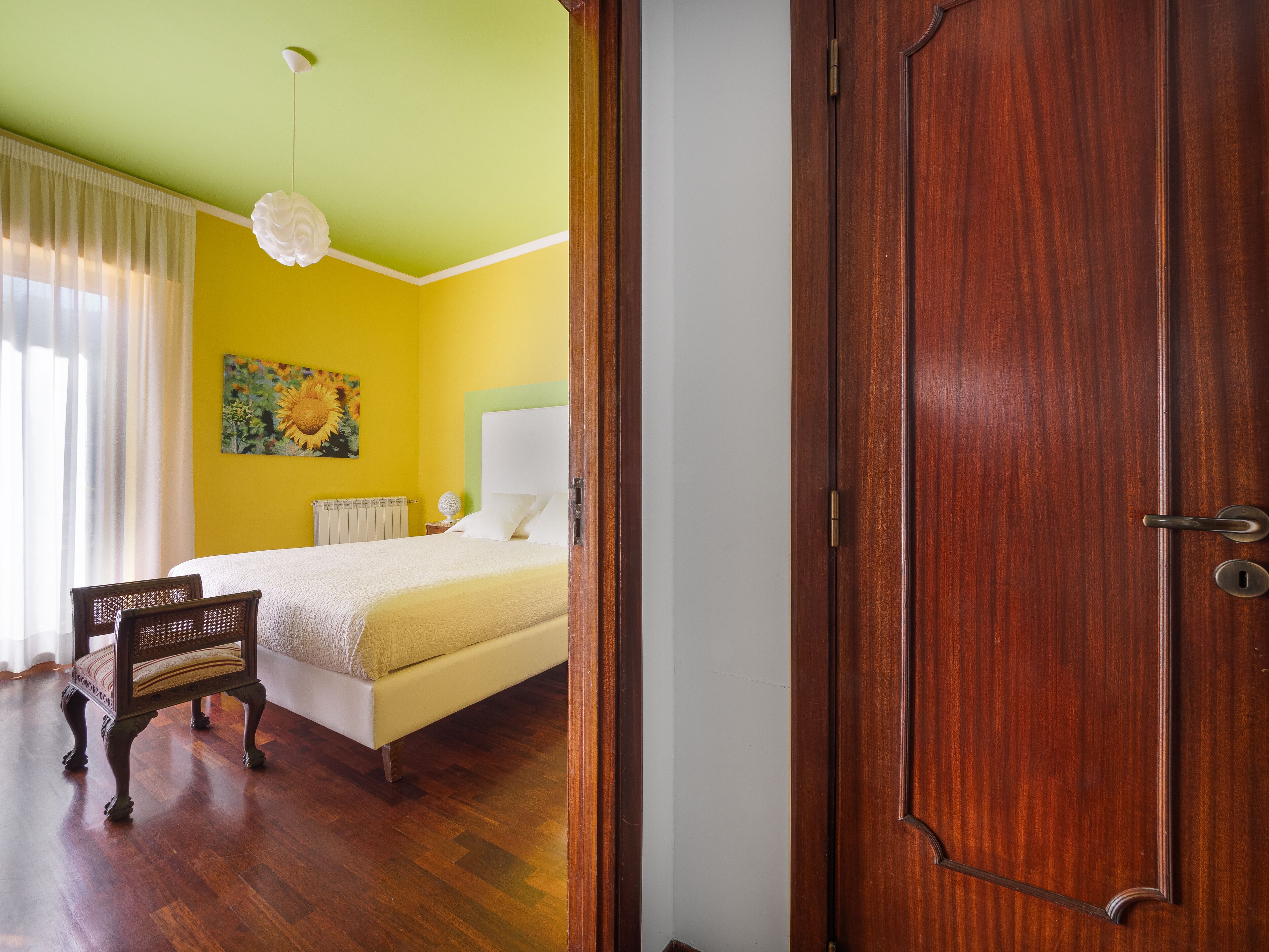 A room with a bed, a chair, a radiator, and a painting on the wall.