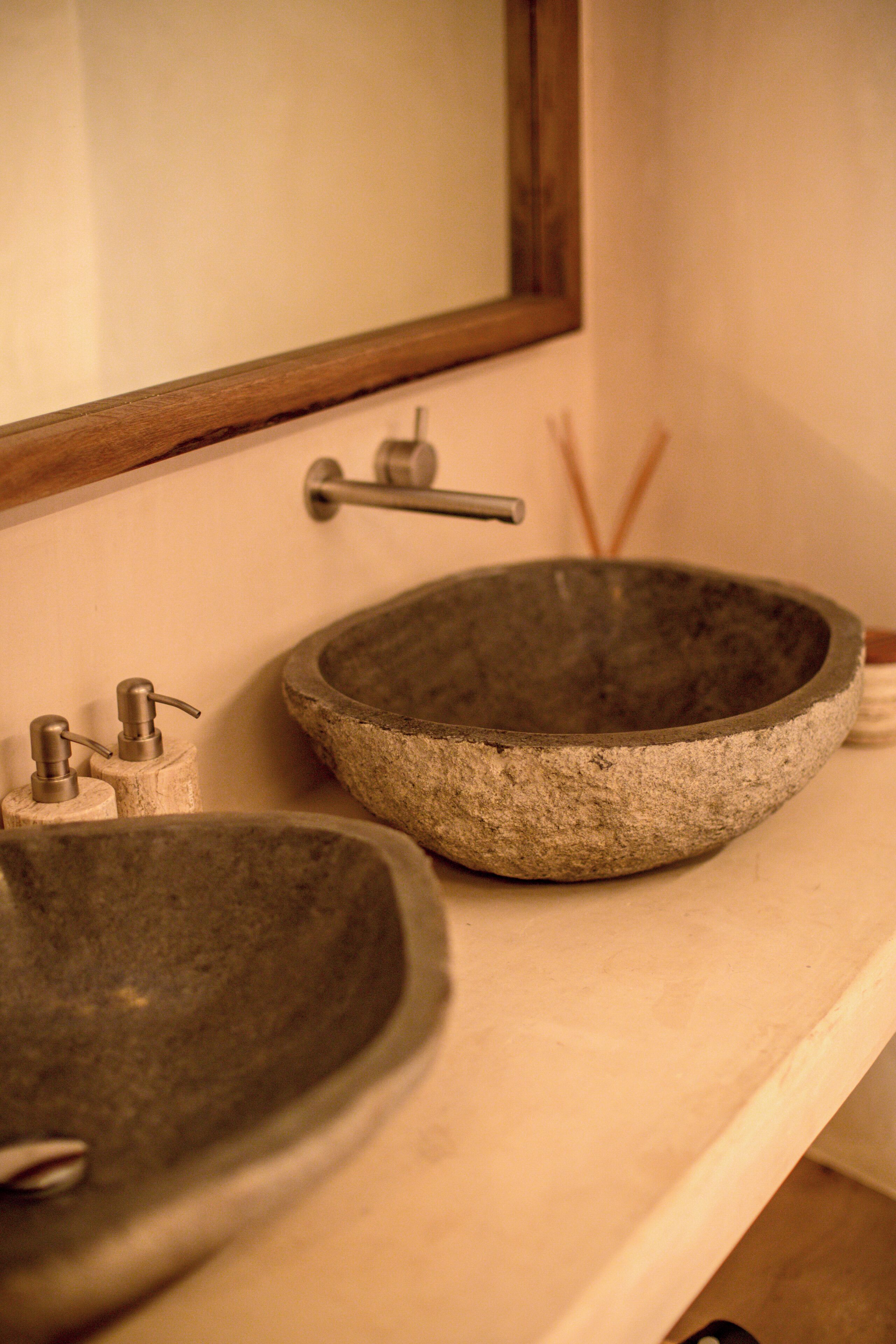 A bathroom with a stone sink and a mirror above it.