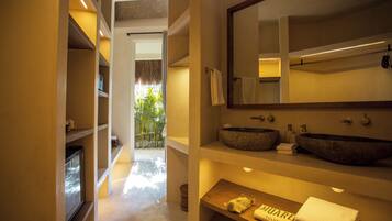 Un baño moderno con un espejo grande, dos lavamanos de piedra y un estante de madera con toallas.