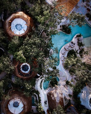 An aerial view of a resort with multiple circular structures, a central pool, and surrounding lounge areas. - Hotel Muarè Tulum Wellness & Spa (Tulum)