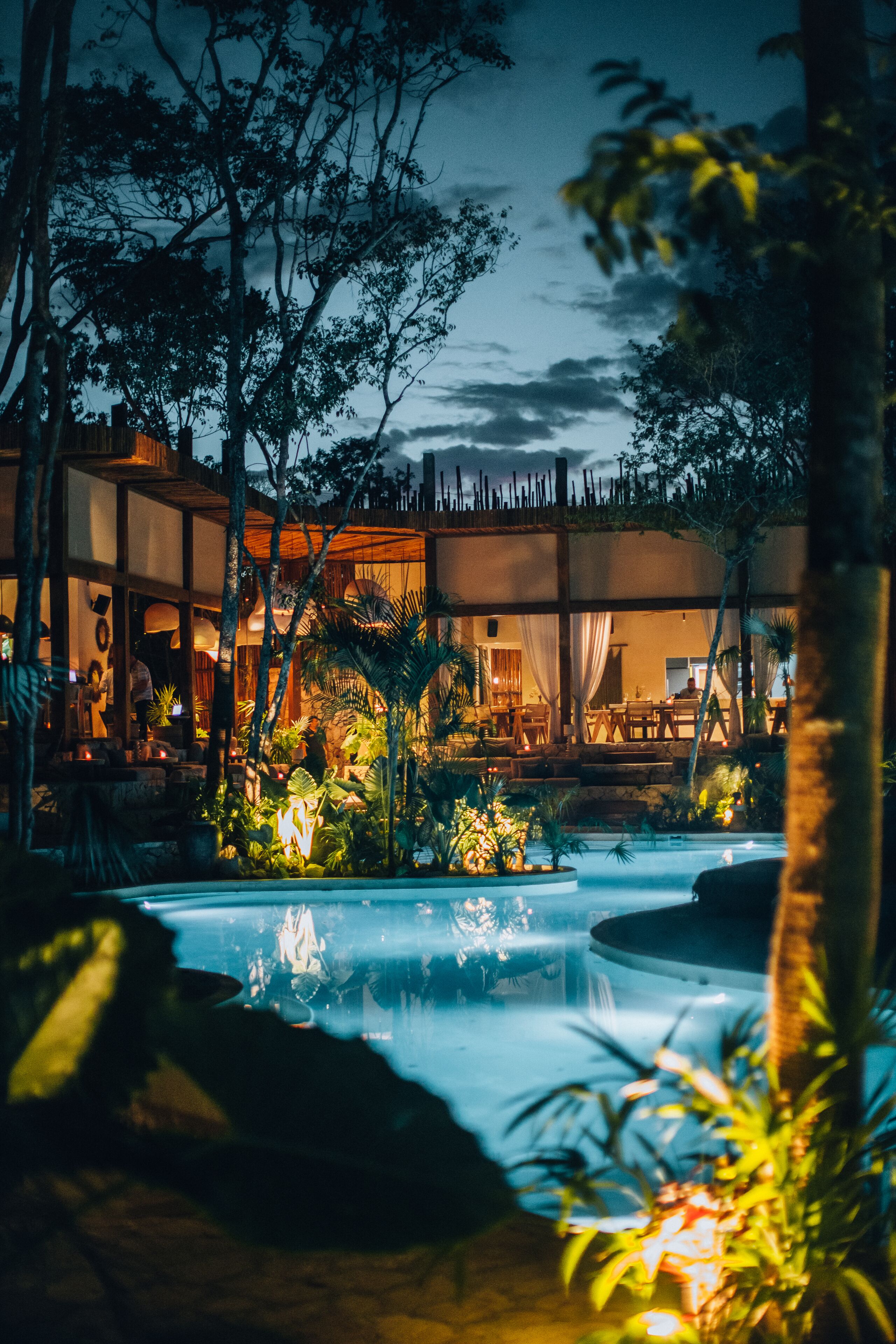 A resort with a pool, outdoor seating, and lush vegetation.